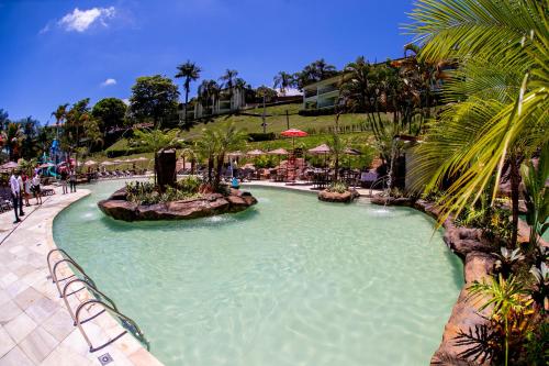 a large swimming pool in a resort with palm trees at Tauá Hotel & Convention Caeté in Caeté