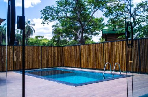 a swimming pool in a backyard with a wooden fence at Casas 3 Encantos in Santana do Riacho