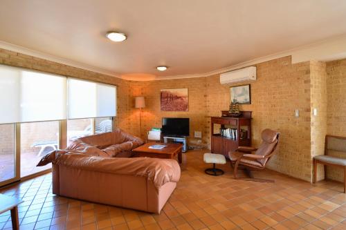 a living room with a leather couch and a television at 9A Bell Street in Rockingham