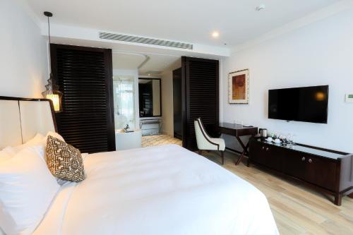 a bedroom with a large white bed and a television at Montgomerie Links Hotel & Villas in Hoi An