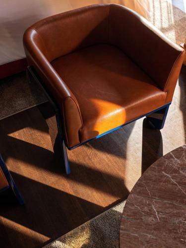 a brown chair sitting next to a table at The Manner, The Unbound Collection by Hyatt in New York
