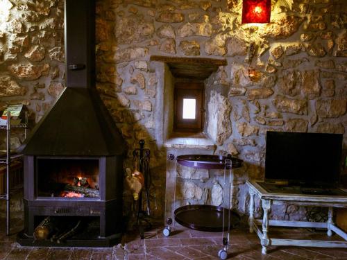 a stone room with a fireplace and a television at Belvilla by OYO Can Guilella in Montmajor