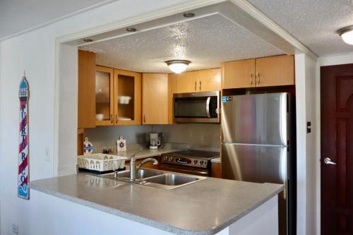 a kitchen with stainless steel appliances and wooden cabinets at Oceanfront Isla Verde 2B 2B Apartment Paradise Getaway in San Juan