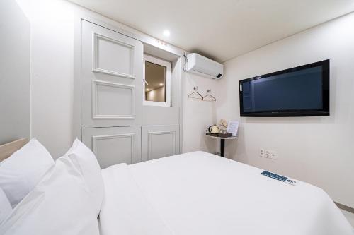 a white bedroom with a large bed and a flat screen tv at SimpleStay Hotel in Jongno in Seoul