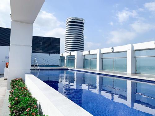 a swimming pool in front of a building with a tower at Departamento con Piscina, Jacuzzi y GYM in Guayaquil