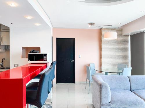 a living room with a red table and chairs at Departamento con Piscina, Jacuzzi y GYM in Guayaquil