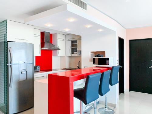 a kitchen with red and white cabinets and blue chairs at Departamento con Piscina, Jacuzzi y GYM in Guayaquil