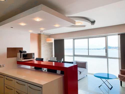 a kitchen with a red desk and a living room at Departamento con Piscina, Jacuzzi y GYM in Guayaquil