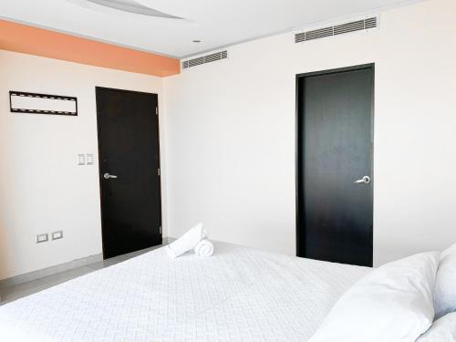 a bedroom with two black doors and a white bed at Departamento con Piscina, Jacuzzi y GYM in Guayaquil