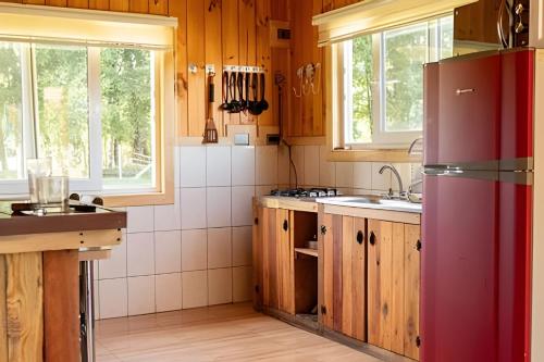 a kitchen with wooden cabinets and a red refrigerator at Parque Vera Cabaña 1 in Melipeuco