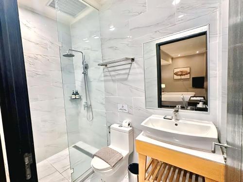a bathroom with a sink and a shower with a mirror at Le Charmé Suites - Subic in Olongapo