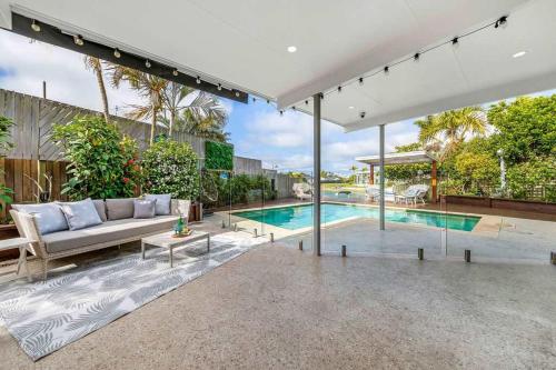 a living room with a couch and a swimming pool at Luxury 5-Bedroom Canal-Front Retreat in Mooloolaba in Mooloolaba