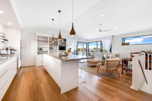 a kitchen and living room with white walls and wood floors at Luxury 5-Bedroom Canal-Front Retreat in Mooloolaba in Mooloolaba