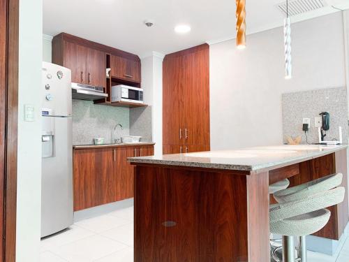 a kitchen with wooden cabinets and a white refrigerator at Departamento con Piscina, Jacuzzi y GYM in Guayaquil