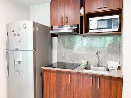 a kitchen with a white refrigerator and a sink at Departamento con Piscina, Jacuzzi y GYM in Guayaquil