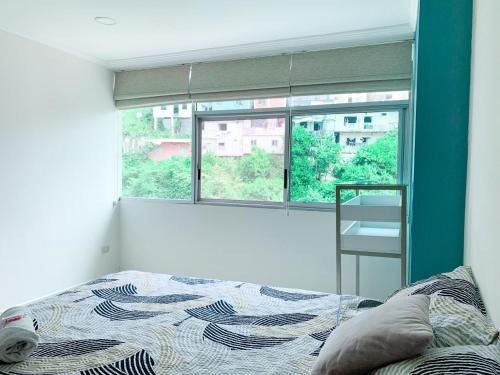 a bedroom with a bed in front of a window at Departamento con Piscina, Jacuzzi y GYM in Guayaquil