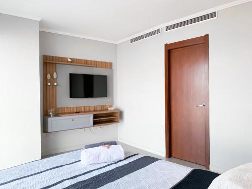 a bedroom with a bed and a tv on the wall at Departamento con Piscina, Jacuzzi y GYM in Guayaquil