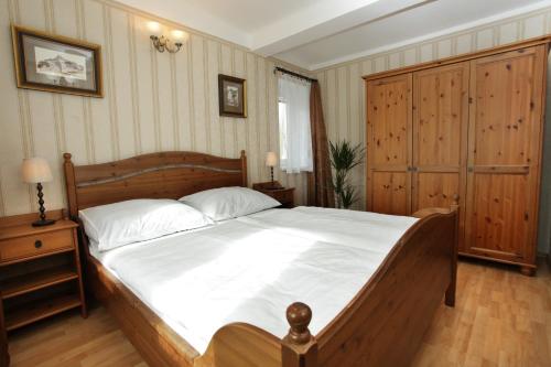a bedroom with a large wooden bed with white sheets at Hotel Štekl - Hrubá Skála in Hrubá Skála