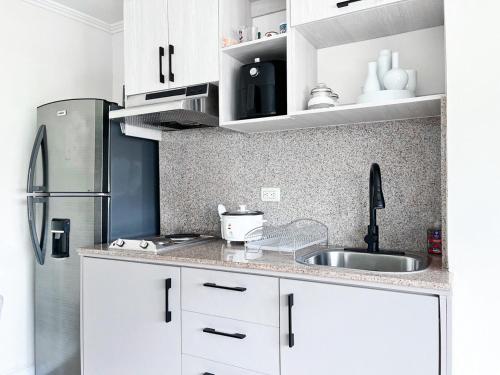 a kitchen with white cabinets and a stainless steel refrigerator at Departamento con Piscina, Jacuzzi y GYM in Guayaquil