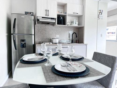 a kitchen with a table with plates and wine glasses at Departamento con Piscina, Jacuzzi y GYM in Guayaquil