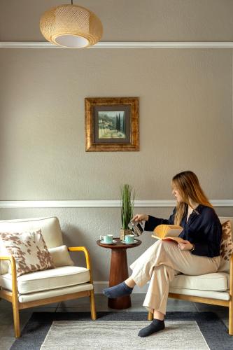 a woman sitting on a couch reading a book at Blair House Inn and Spa in Wimberley