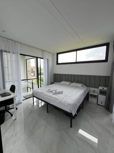 a bedroom with a bed and a desk and windows at Villa Tres Adam in Canggu