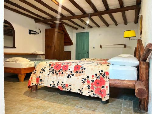 a bedroom with a bed with a floral bedspread at Posada Luisa Del Valle Guacuco in Playa Guacuco