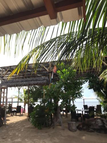 a patio with a palm tree and tables and chairs at Saeri Matahari Bungalow in Gili Air