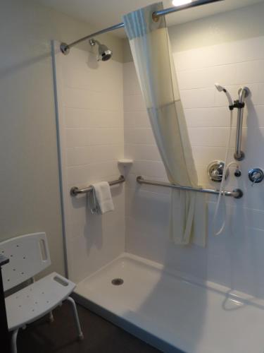 a bathroom with a tub and a shower with a mirror at MainStay Suites Denver International Airport in Denver