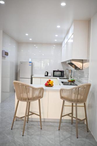 a white kitchen with two chairs and a counter at JJY Apartment in Nadi