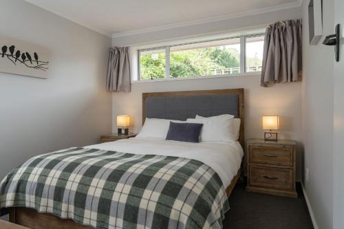 ein Schlafzimmer mit einem Bett mit einer karierten Decke und einem Fenster in der Unterkunft Roselle Farm Cottage in Portobello