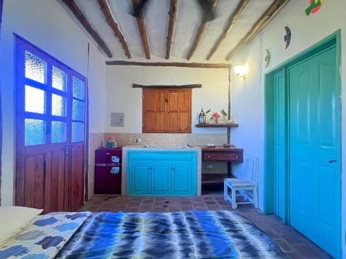 a kitchen with blue cabinets and a bed in a room at Posada Luisa Del Valle Guacuco in Playa Guacuco