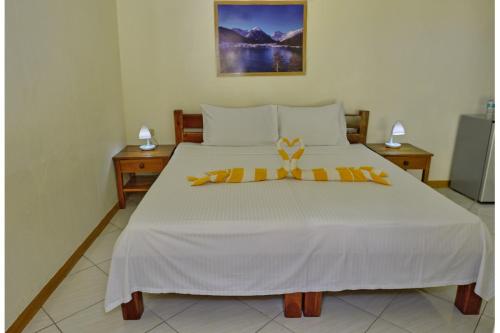 a bedroom with a large white bed with yellow decorations on it at Alona Austria Resort in Panglao