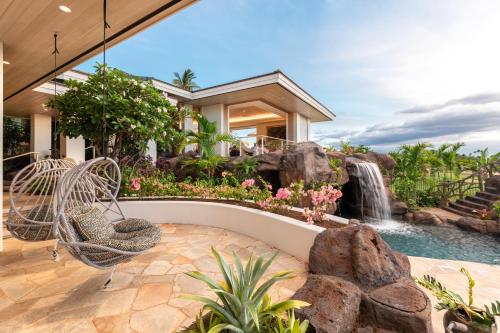 a backyard with a waterfall and a swing and a house at Hale 'O Ka La in Hapuna Beach