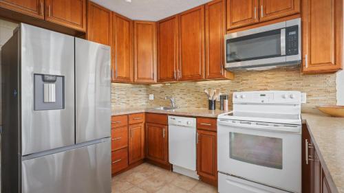 a kitchen with white appliances and wooden cabinets at Hale Makani in Kailua-Kona