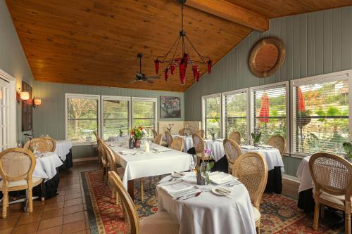 a restaurant with white tables and chairs and windows at Blair House Inn and Spa in Wimberley