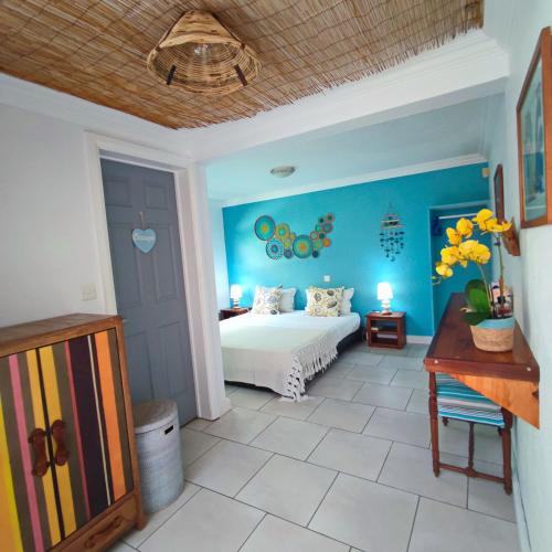 a bedroom with a bed and a blue wall at sweet island studio ocean in Rivière Noire