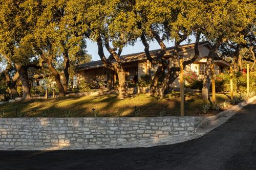 a house with trees and a stone wall at Blair House Inn and Spa in Wimberley