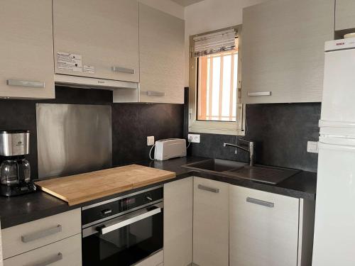 une cuisine avec des armoires blanches et un évier dans l'établissement Superbe T3 au Lavandou avec balcon et parking - FR-1-308-205, au Lavandou