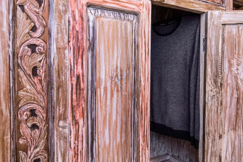 a wooden cabinet with ajar door with a black shirt at Elafos Spa Hotel in Elliniko