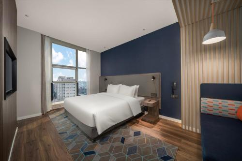 a bedroom with a white bed and a blue wall at Holiday Inn Express Zhengzhou Guancheng by IHG in Zhengzhou