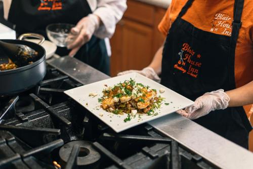 a person holding a plate of food on a stove at Blair House Inn and Spa in Wimberley