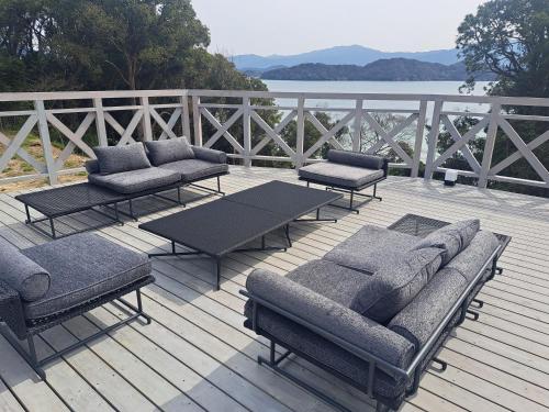 a deck with couches and a table and chairs at lastpiece in Itoshima