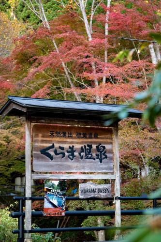 a sign with asian writing on it in front of trees at くらま温泉 in Kyoto