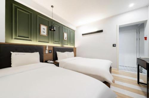 two beds in a room with green cabinets at Hotel Yoegieottae Gwangju Hanam in Gwangju