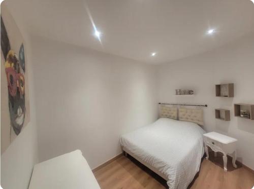 Cette petite chambre blanche comprend un lit et une table. dans l'établissement Appartement plein centre ville place des vosges, à Épinal