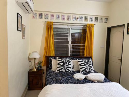 una camera da letto con un letto con cuscini e una finestra di Gachibowli ' House of Color's Susi Stays-303 1 BHK a Gachibowli