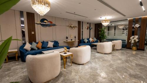 a living room with a blue couch and white chairs at Brzeen Hotel Riyadh in Riyadh