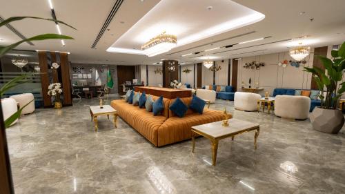 a lobby with a couch and tables and chairs at Brzeen Hotel Riyadh in Riyadh
