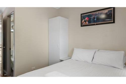 a bedroom with a white bed with a picture on the wall at Discovery Parks - Port Hedland in Port Hedland